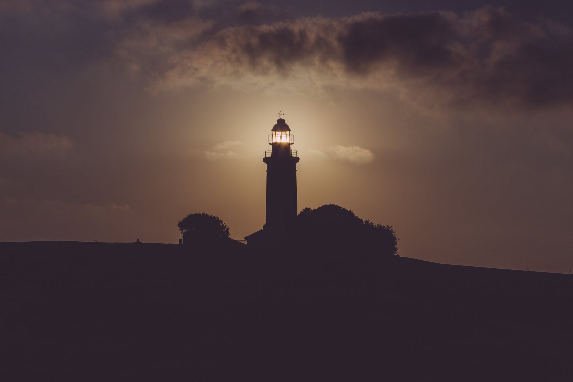 Silhouette of lighthouse against dusky sky.